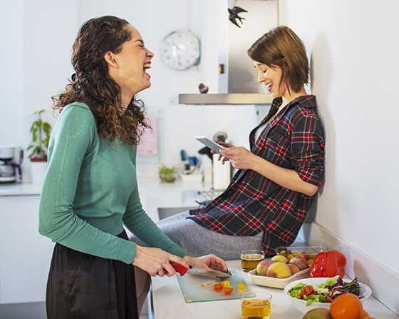 Dos chicas comiendo verduras en la cocina